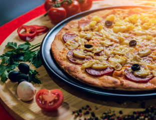 Large hot pizza on the black plate.