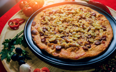 Large hot pizza on the black plate.