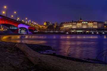 Fototapeta na wymiar Zamek Królewski - Royal Castle in Warsaw as seen by night with a bridge and a river reflection