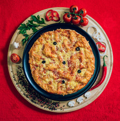 Large hot pizza on the black plate.