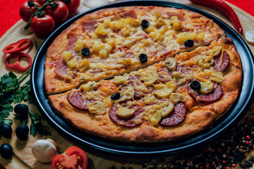 Large hot pizza on the black plate.