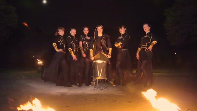 Man with a group of girls playing the drum burning. Against the backdrop of flashing lights
