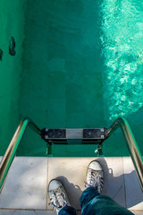 Mann in Sneakers und Jeans steht an Leiter am Pool in Luxus Resort in Lecce, Italien