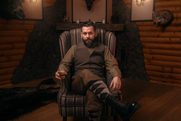 Hunter man sitting in a chair and drink whiskey