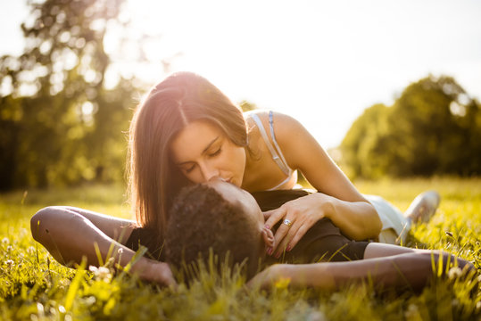 Sunny romance - young couple kissing in grass