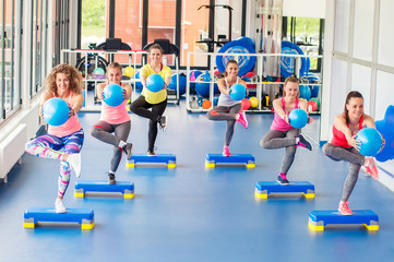 Group of beautiful young women working out on blue stepper and smiling.