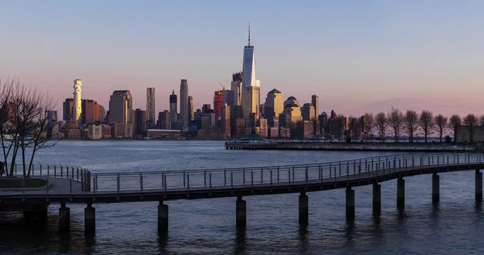 New York City Lower Manhattan cityscape view from Hoboken (NJ). Sunset to twilight time-lapse with piers, pedestrian bridge and skyscrapers