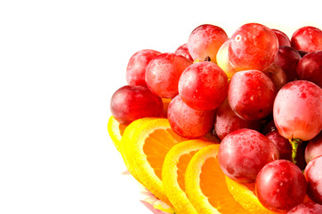 plate with oranges and grapes on white background