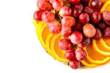 plate with oranges and grapes on white background