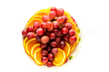 plate with oranges and grapes on white background