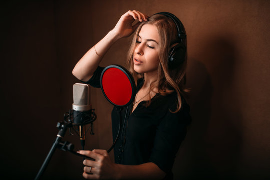 Female singer recording a song in music studio