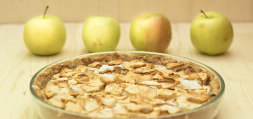 The apple pie with green apples at the wood table
