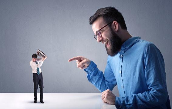 Young businessman fighting with miniature businessman