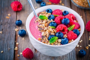 Breakfast smoothie bowl  with granola, fresh raspberry, blueberry, chia seeds and mint