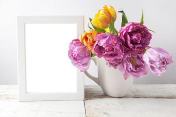 Fresh tulip flowers bouquet and blank photo frame with copy space on wooden background