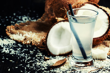 Refreshing coconut water in a glass, black background, selective focus