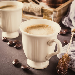 Two retro cups of coffee and old coffee pot on dark brown background. Retro style toned.