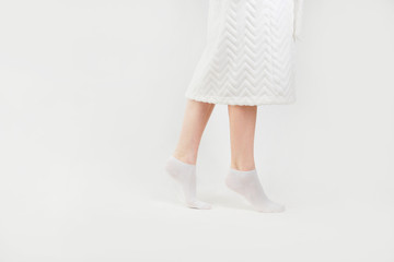 Slender beautiful female legs in socks walking on tiptoe, side view, isolated on white background.