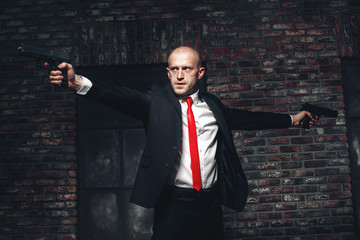 Bald hired killer in red tie aims a pistols