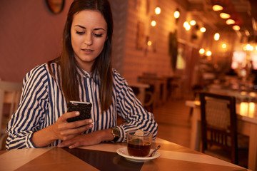 Pensive millenial in restaurant with phone