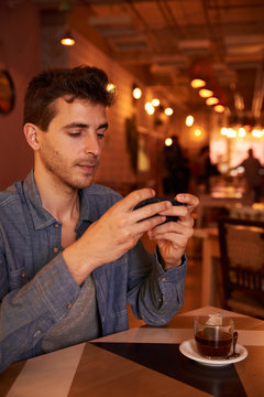 Attractive millenial texting in a restaurant