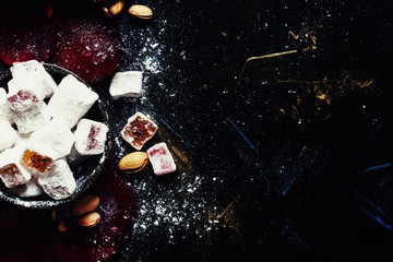 Eastern sweets with sugar powder, pistachios and rose petals, food background, top view
