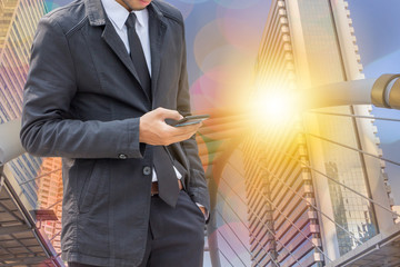 Close up of young business man using mobile smartphone at outside office sunset double exposure city background.