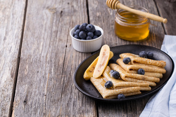Crepes with honey on wooden background