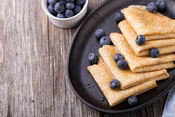 Crepes with honey on wooden background