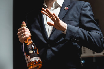 Fototapeta premium Sommelier in a dark blue jacket holding a bottle of wine and tells the audience about the various wines