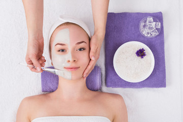 Woman gets face mask by beautician at spa