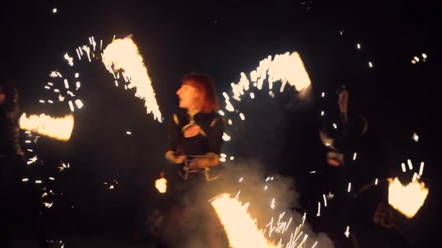 Girls spin fire sparkling fireworks and dancing. Fire show performance