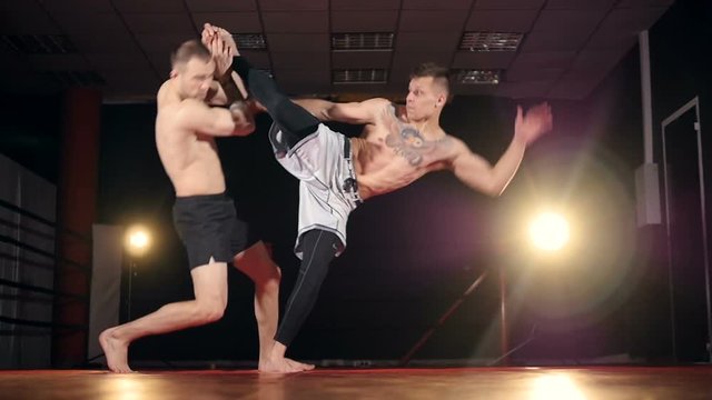 MMA fighter giving a forceful forward kick to his partner. HD.