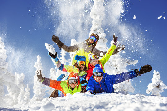 Group of five happy snowboarders and skiers