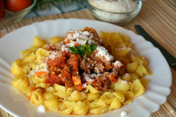 Pasta bolognese with meat and tomato sauce and parmesan on a plate.