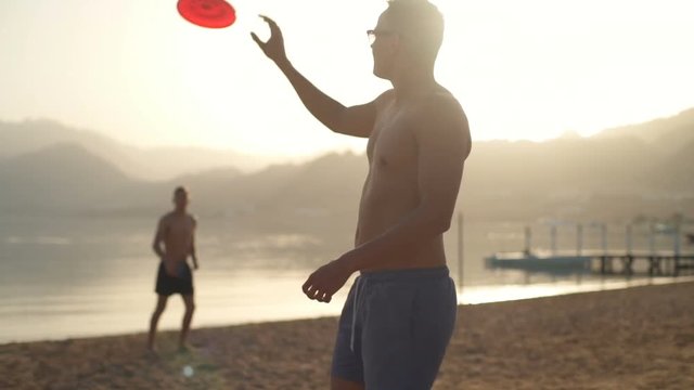 Friends playing frisbee on the beach slow motion