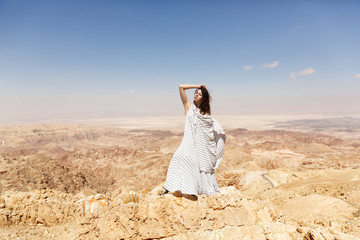 Fototapeta na wymiar Stylish girl, standing in fashion clothes on the mountain, in the background of the desert in Jordan