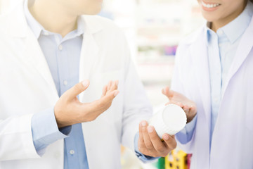 Pharmacist holding medicine bottle and discussing in pharmacy