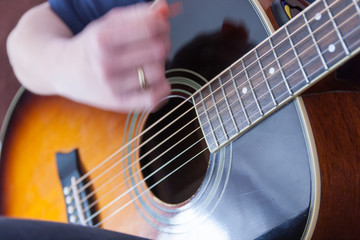 hand playing on an acoustic guitar