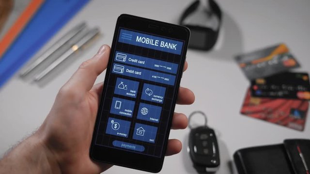Counter payment via mobile banking application on the smartphone. A man transfers money from his credit card to another person.
