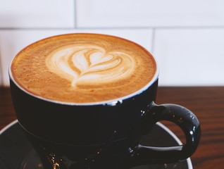 Cup of coffee latte art on wooden table in vintage color tone filter