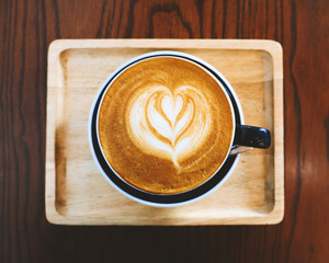 Top view of cup of coffee latte art on wooden table in vintage color tone filter.