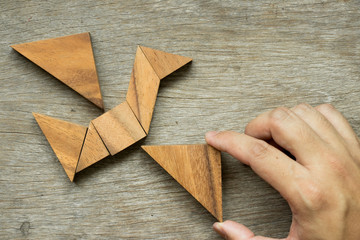 Man hold triangle to fulfill tangram puzzle in bird shape (Concept for freedom, free life or explore new world)