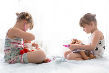 Girls sisters play doctor with dolls, concept maternity