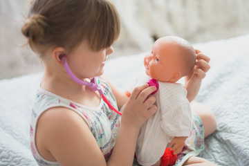 Kid girl playing with doll, playing doctor