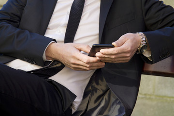 Obraz na płótnie Canvas Businessman sitting in park using mobile phone