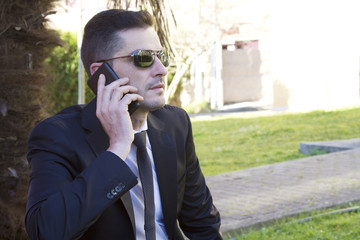 Man in suit sitting in the park talking on the cellphone