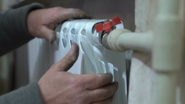 Installation and connection of new hot water radiator by a plumber at home