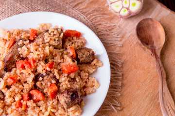 Pilaf on the white plate on a wooden background. Top view. Copy space. Rustic style.