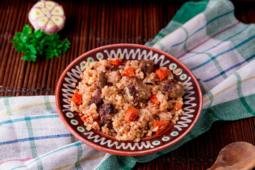 Pilaf on the brown plate on a wooden table, background. Rustic style.